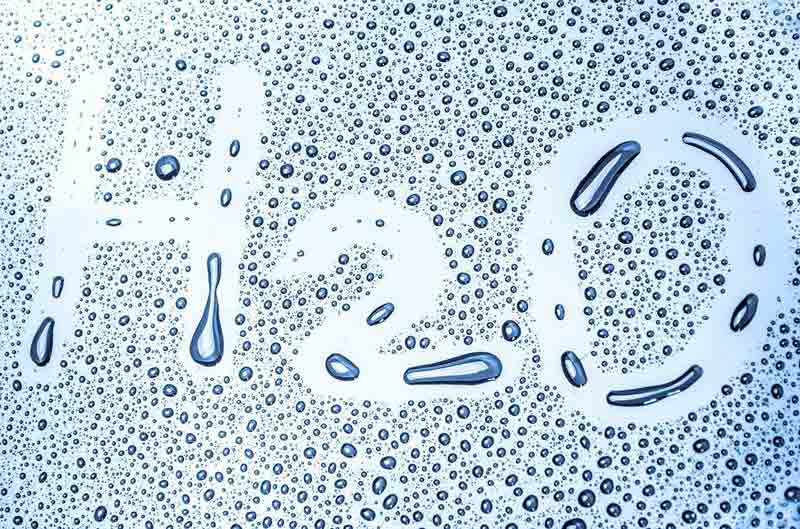 Depiction of humidity that causes water droplets on glass with H2O written in the water.